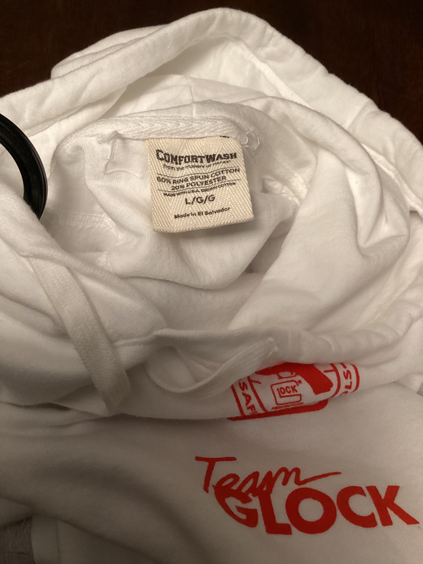 Close-up of GLOCK logo and size tag marked Large on clean white heat hoodie, limited drop edition from ShAesthetics