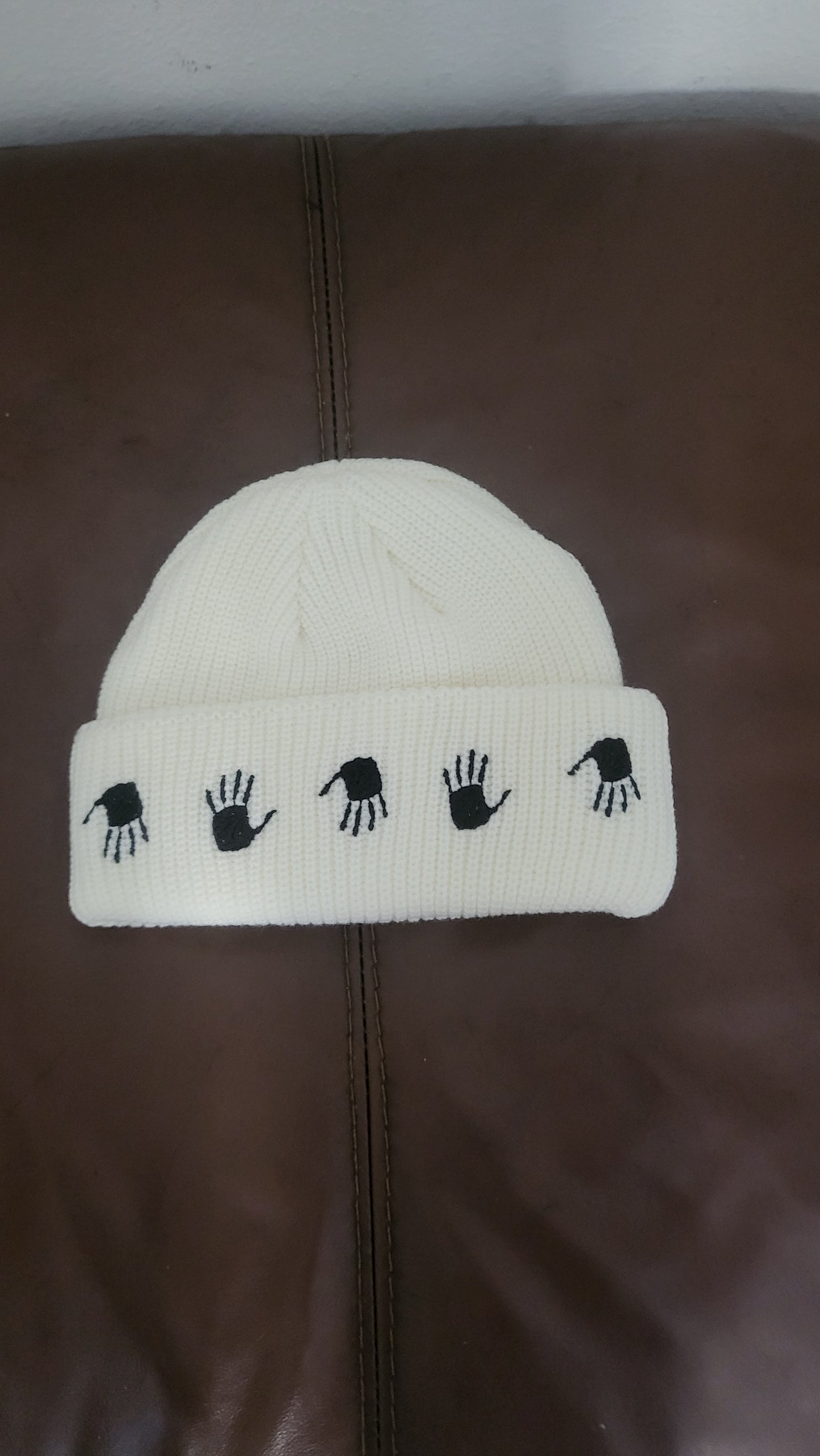 10.Deep Many Hands Beanie in Off White with black hand embroidery on the fold