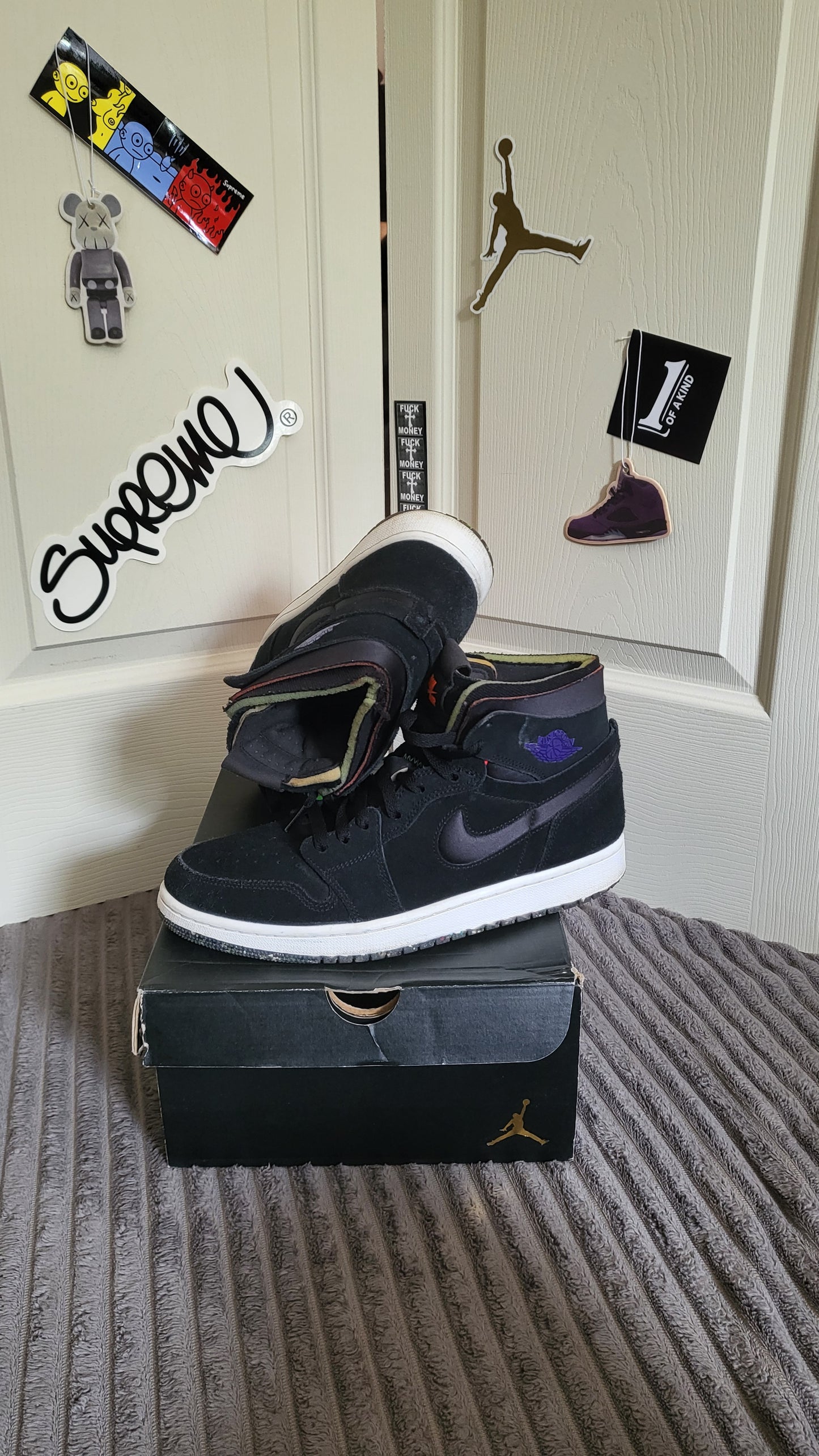 Close-up of the Air Jordan 1 Mid SE in Black/Anthracite with purple accents displayed on top of original Jordan box.