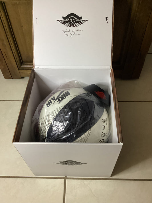 Close-up of Nike Air Jordan basketball inside premium collector’s box with protective plastic wrap, showing iconic Wings logo and Nike branding