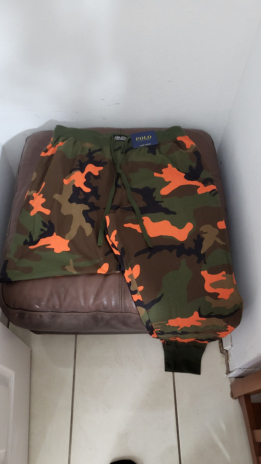 Polo Ralph Lauren camo fleece joggers in blaze orange and olive, size L, displayed on brown leather surface with tags